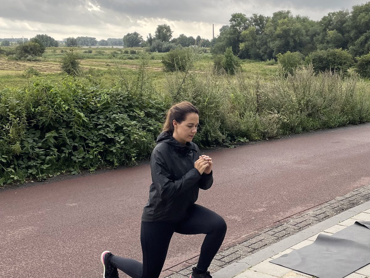 Iemand die vroeg in de ochtend buiten traint op een pad langs een veld